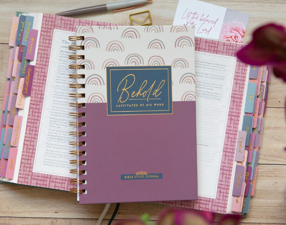 Close-up of a beautifully styled faith-based spiral journal resting on an open devotional planner, surrounded by soft pink tabs and notes, symbolizing intentional study and spiritual reflection.